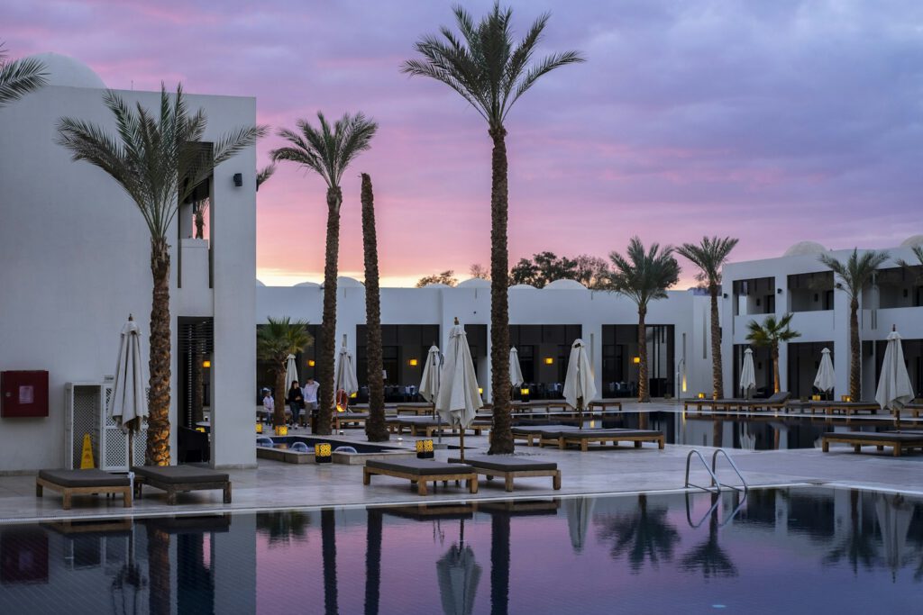 Complexe hôtelier de luxe au crépuscule, piscine et palmiers